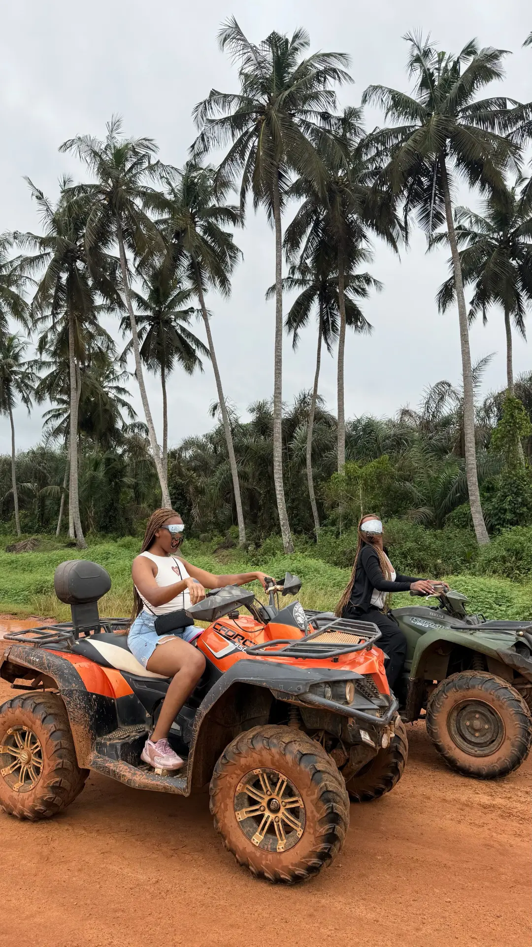 Riders en quad sur la piste rouge d'Assouindé, bordée de palmiers
